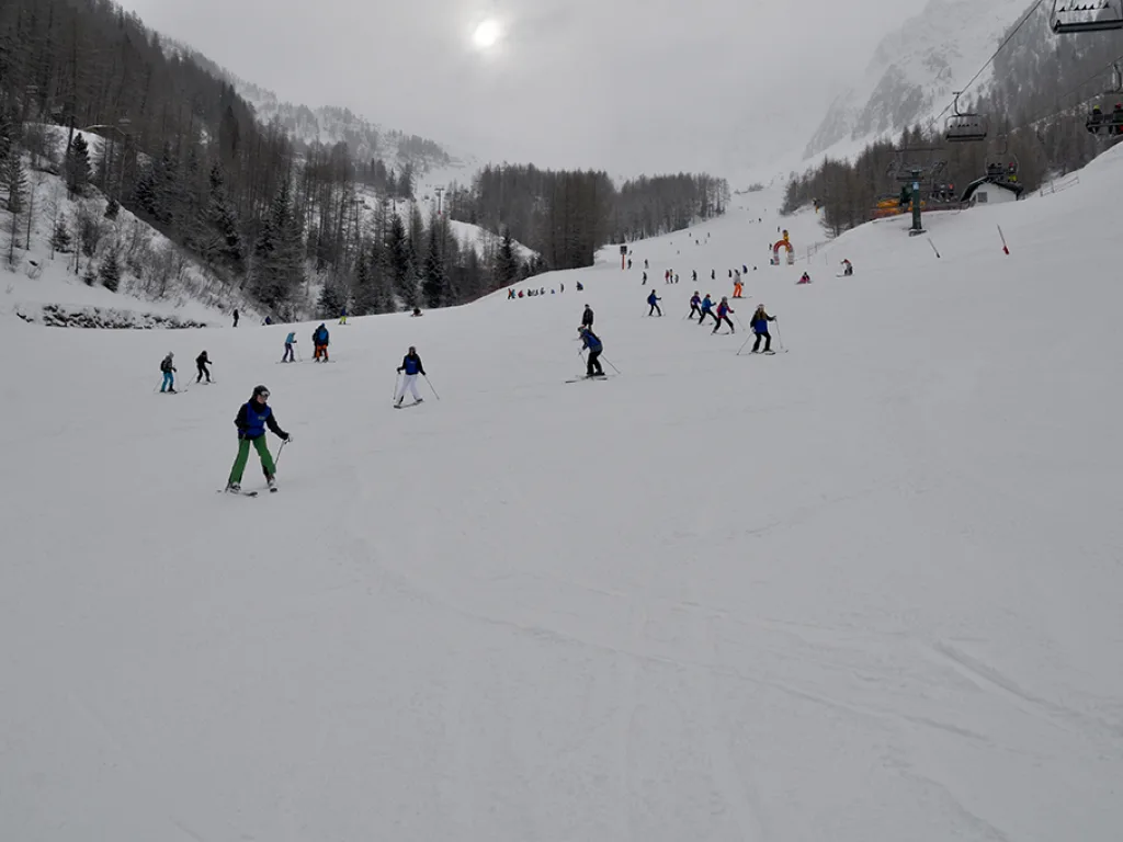 Blick talwärts über die Piste, im Hintergrund Felswände im Dunst.